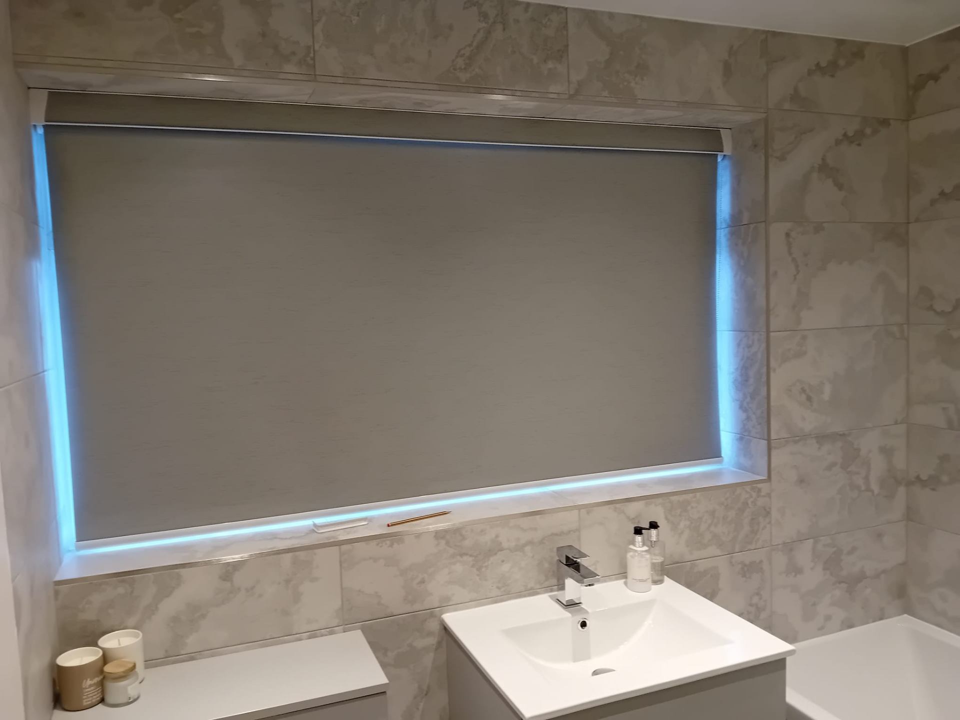 Grey blackout roller blind in a marble tiled bathroom