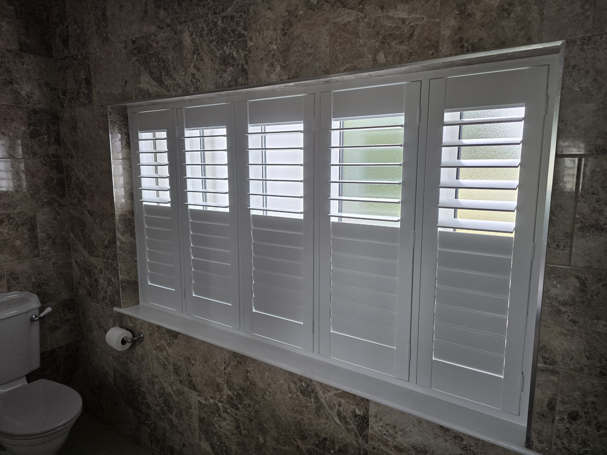 White waterproof plantation shutters in a marble bathroom