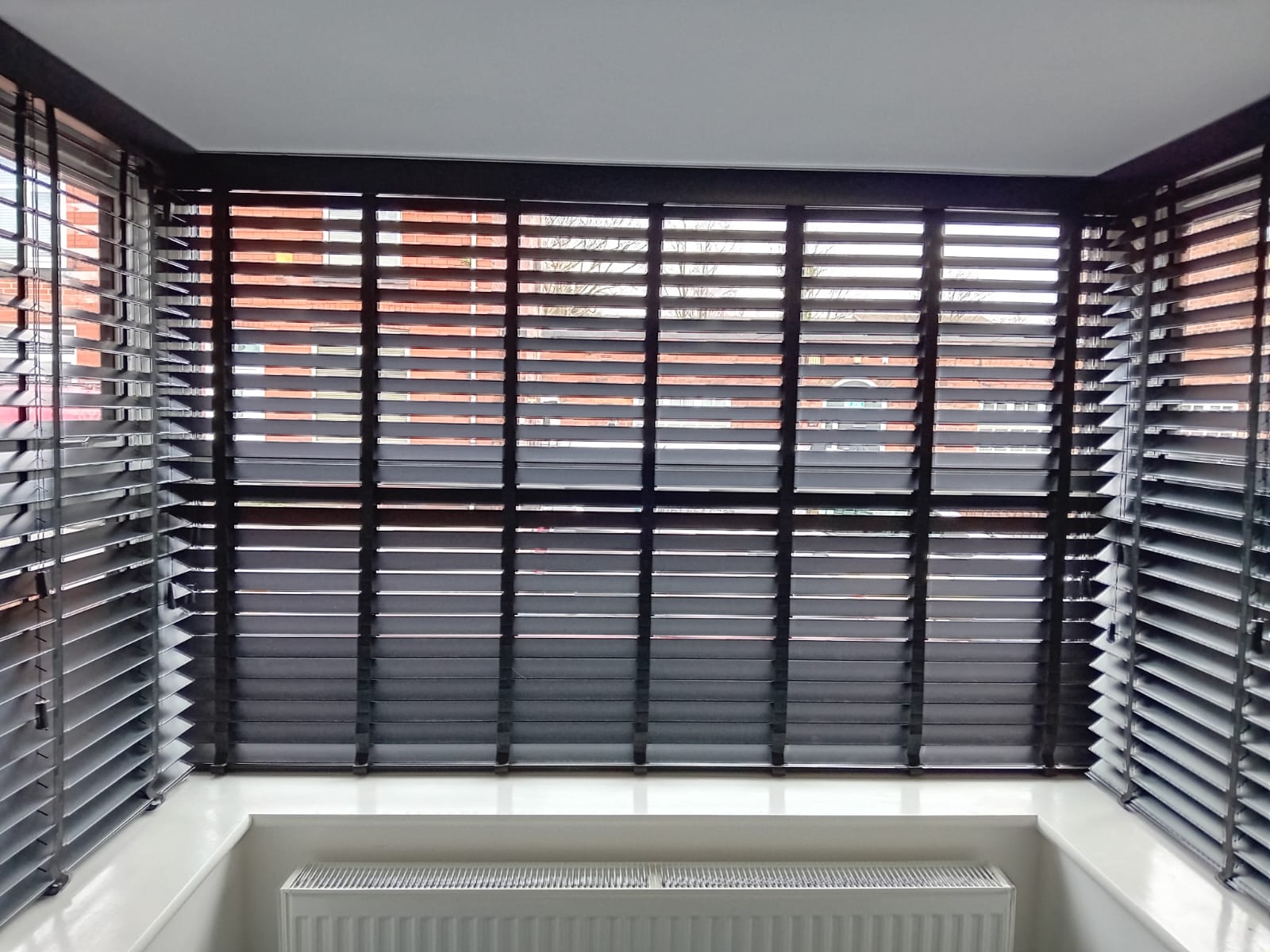 Dark Venetian blinds fitted around a bay window