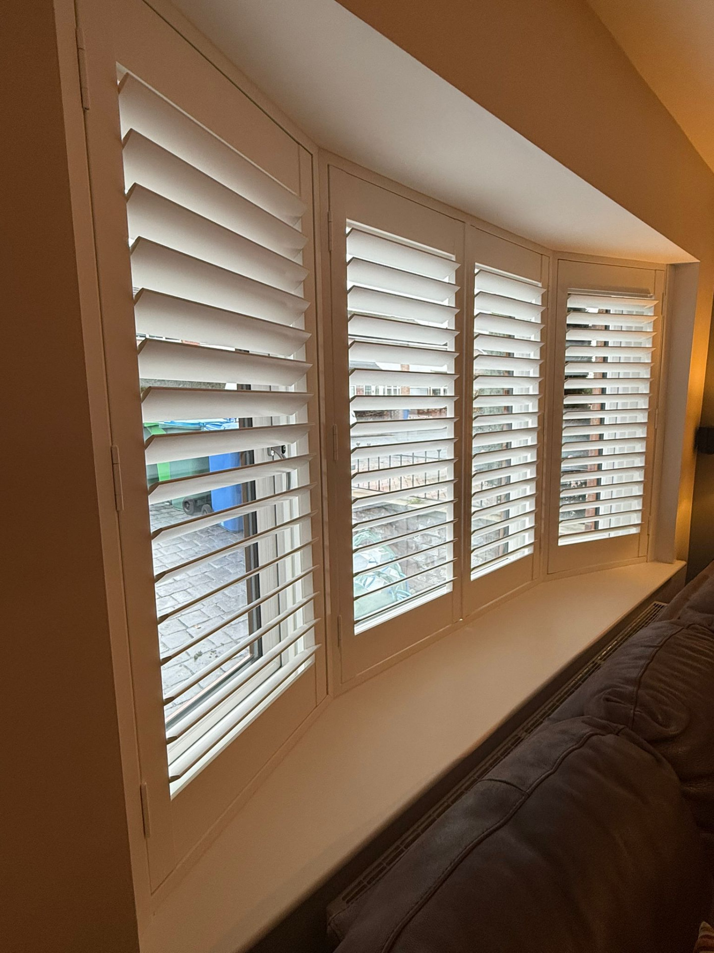 White plantation shutters fitted to a four-panel bay window in a living room