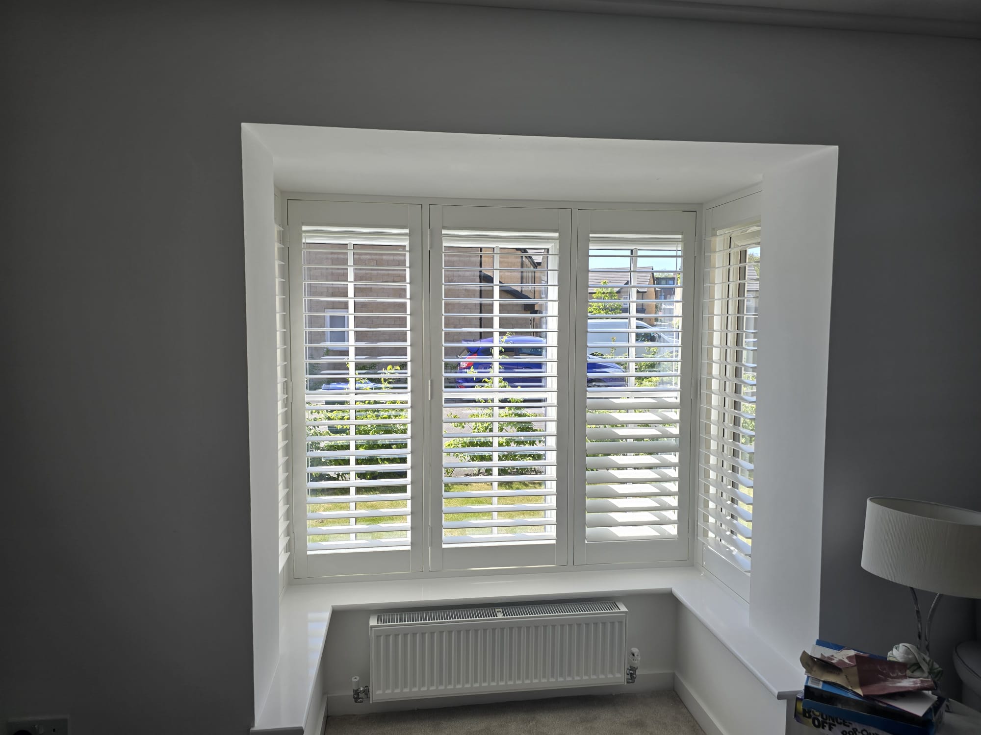 White shutters fitted in a square bay bedroom window