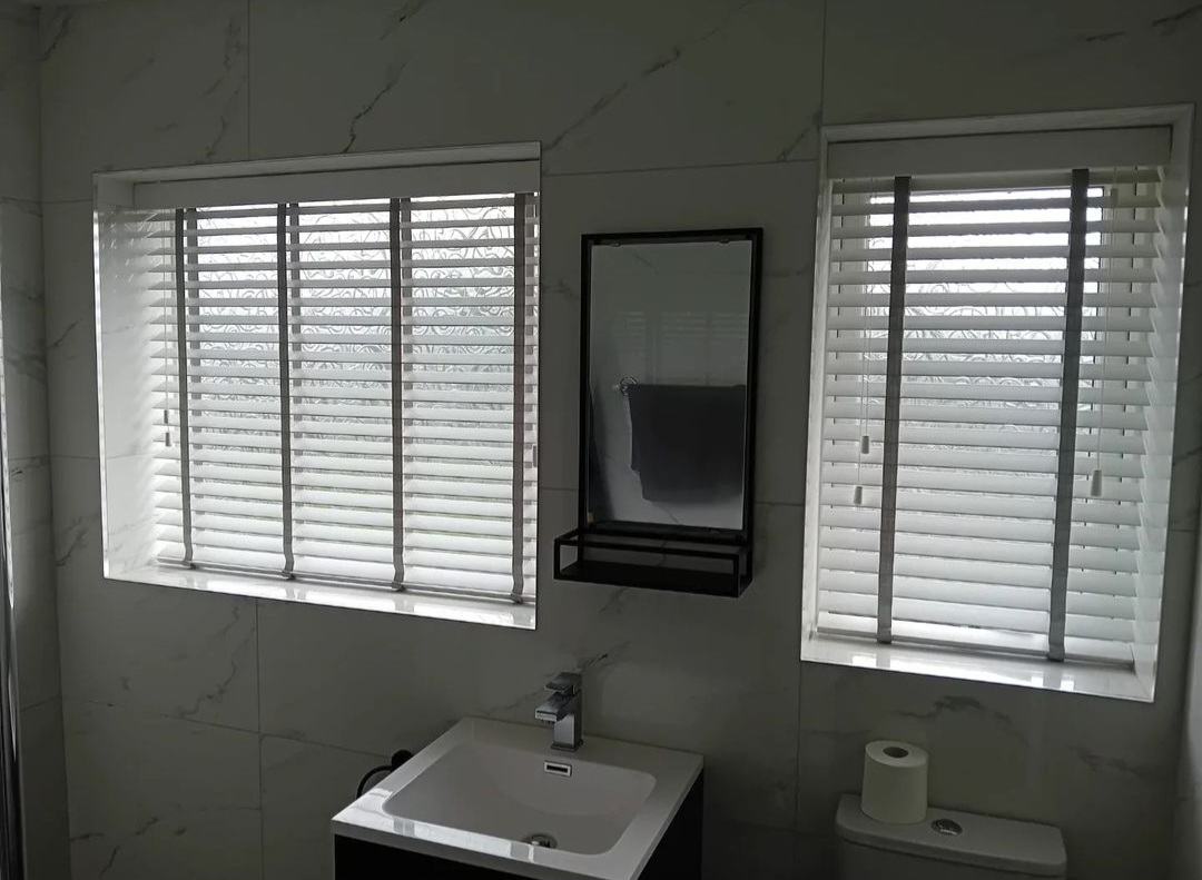 White wooden Venetian blinds in a marble bathroom
