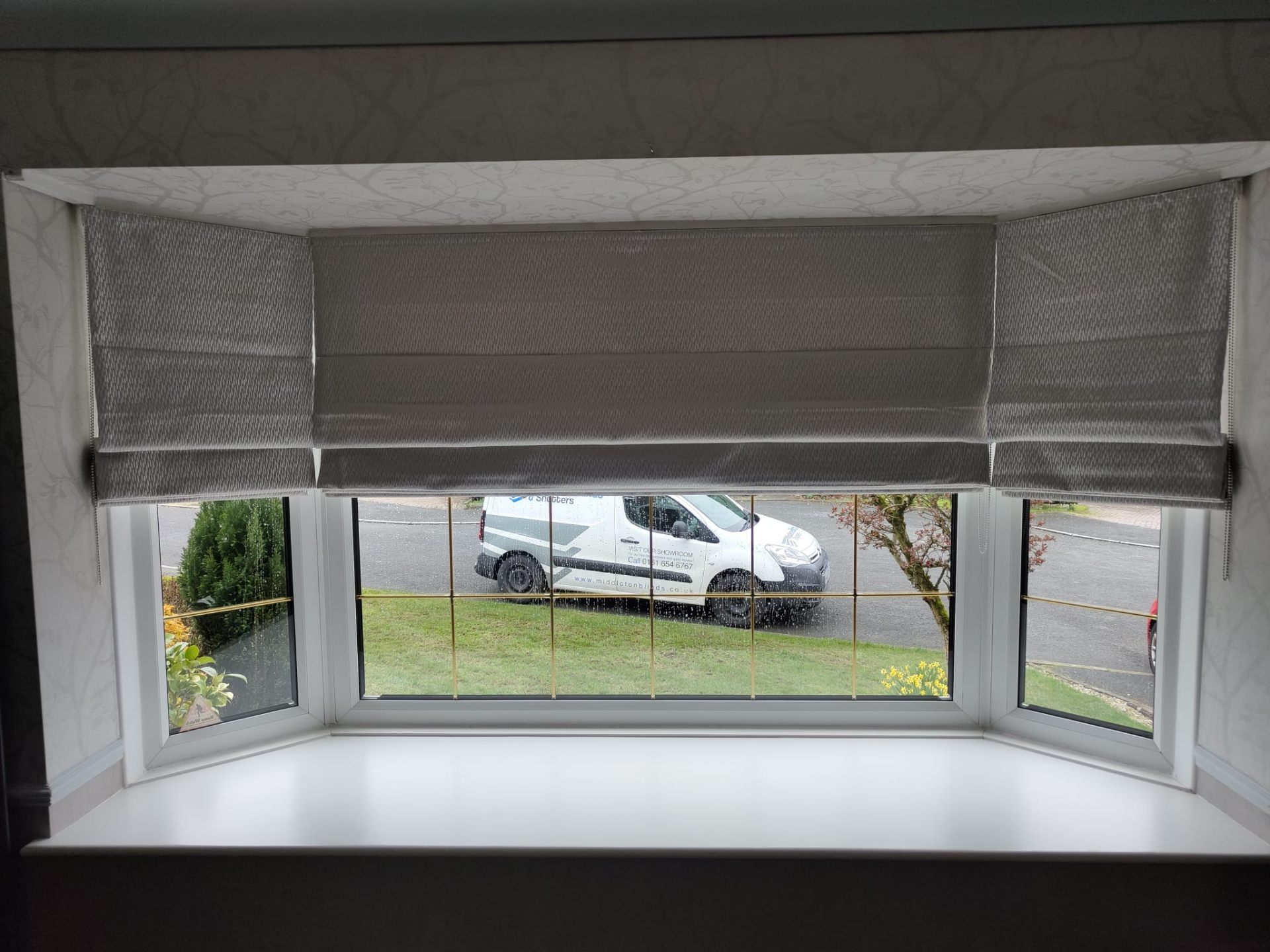 Grey Roman blinds in a bay window