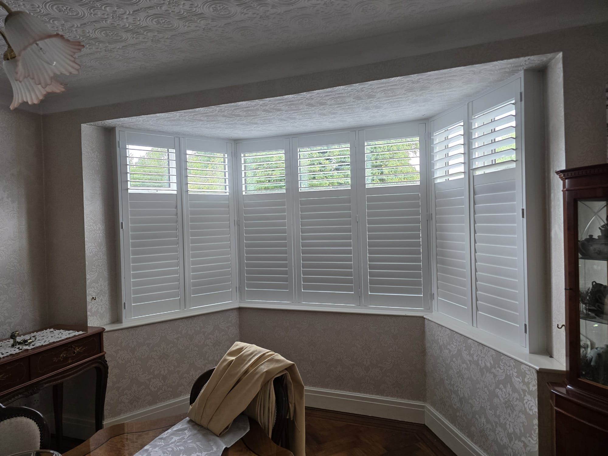 White plantation shutters in a bay window of a Manchester living room