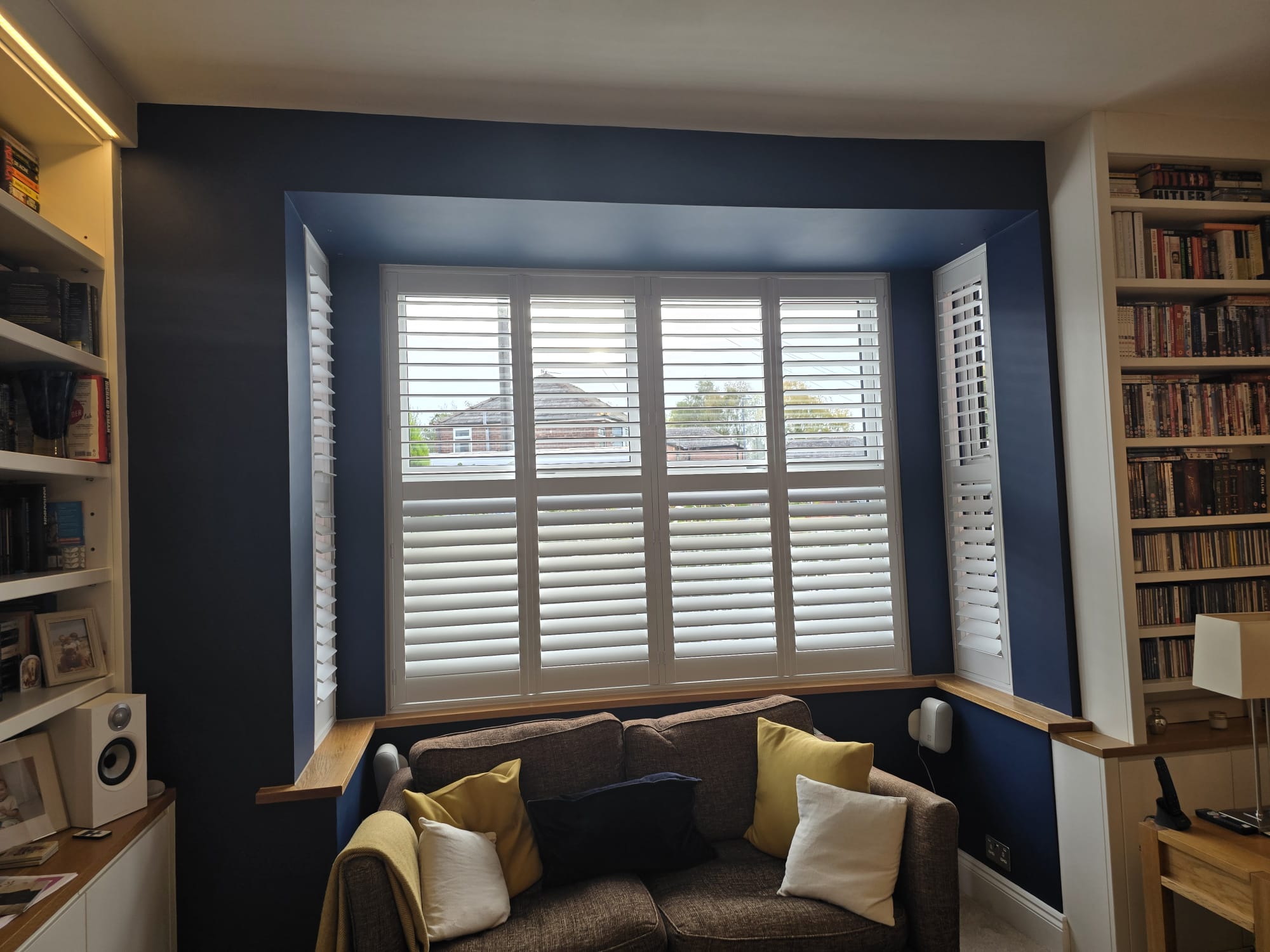 White plantation shutters in a navy blue lounge bay window