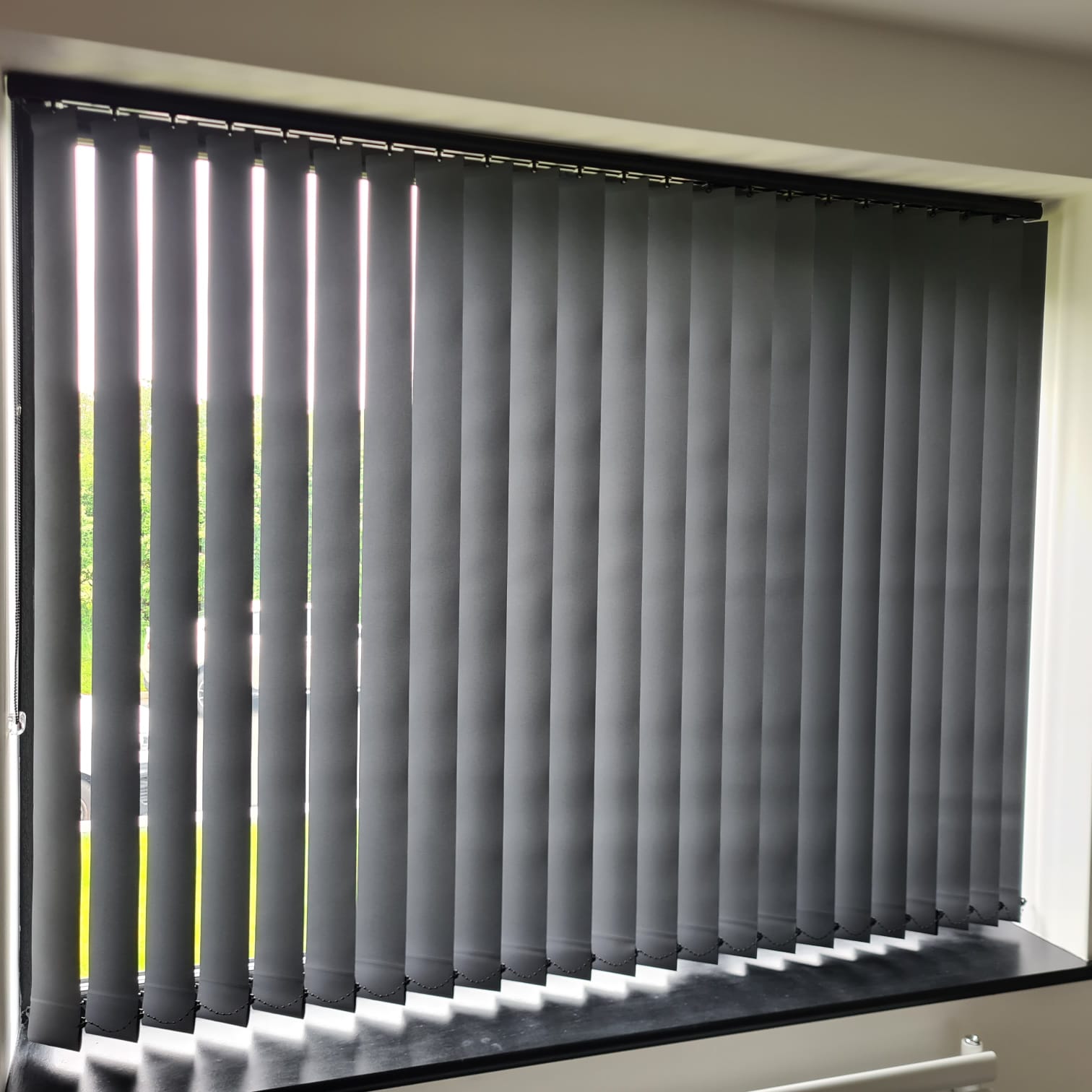 Dark grey vertical blinds fitted across a large window