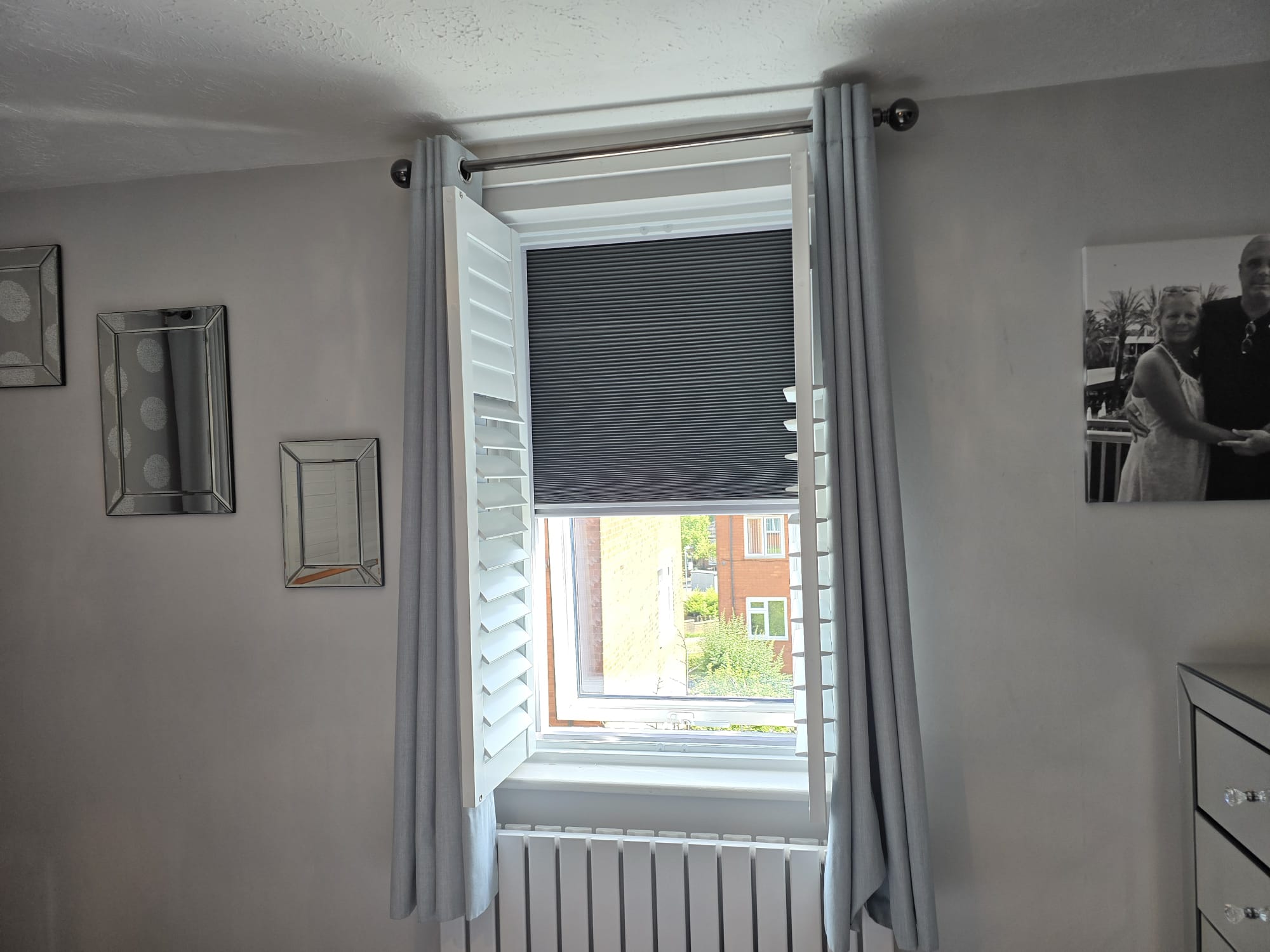 White shutters with a grey pleated blackout blind in a Manchester bedroom
