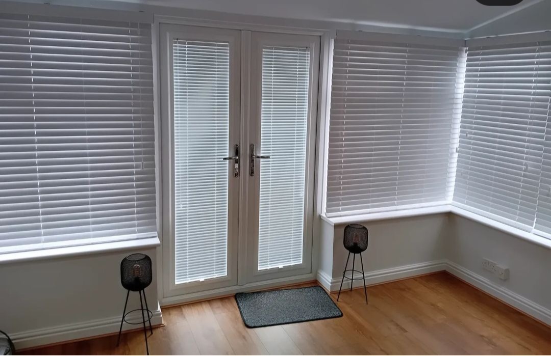 White wooden Venetian blinds in a conservatory