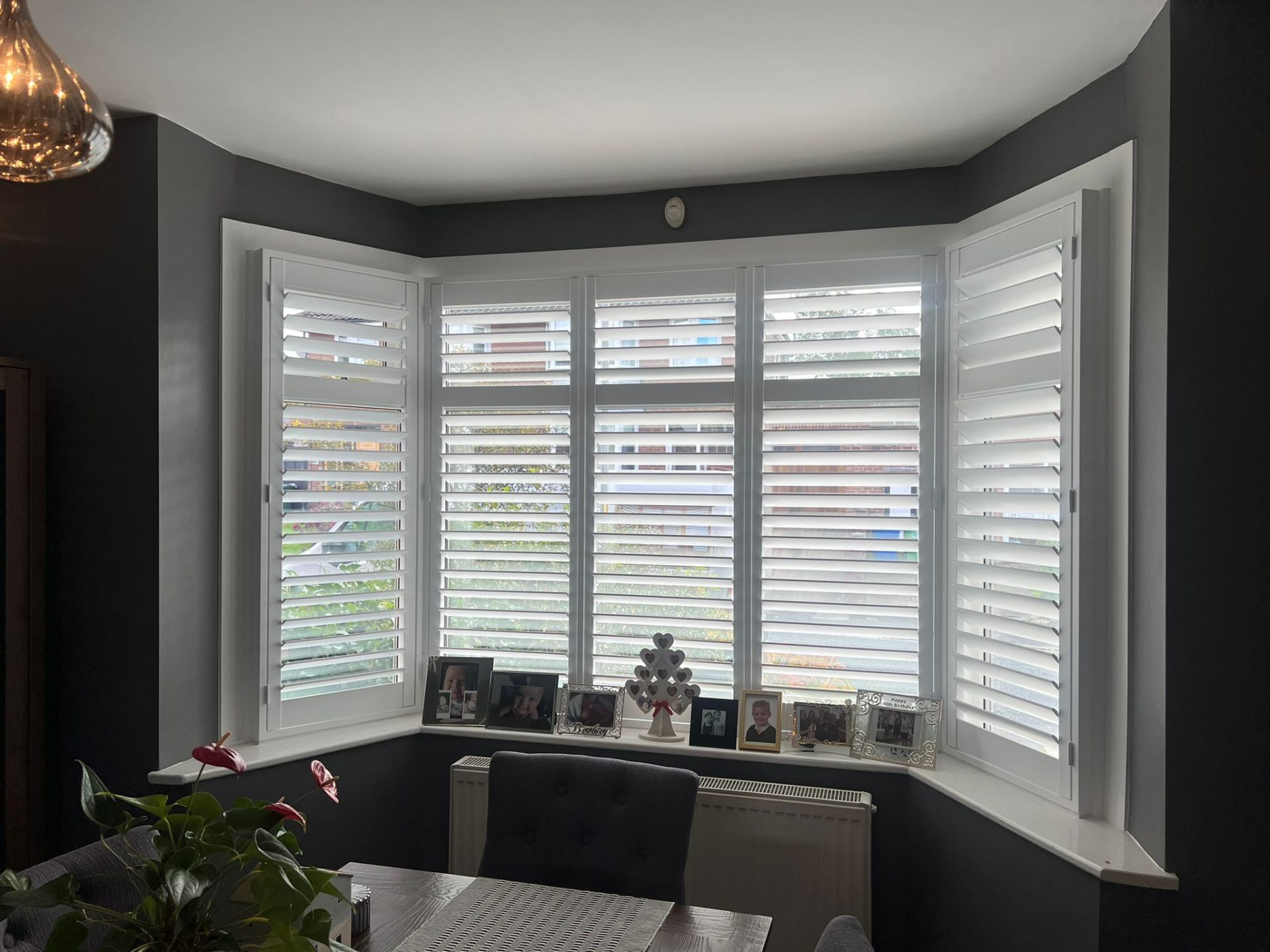 White plantation shutters in a bay window dining room